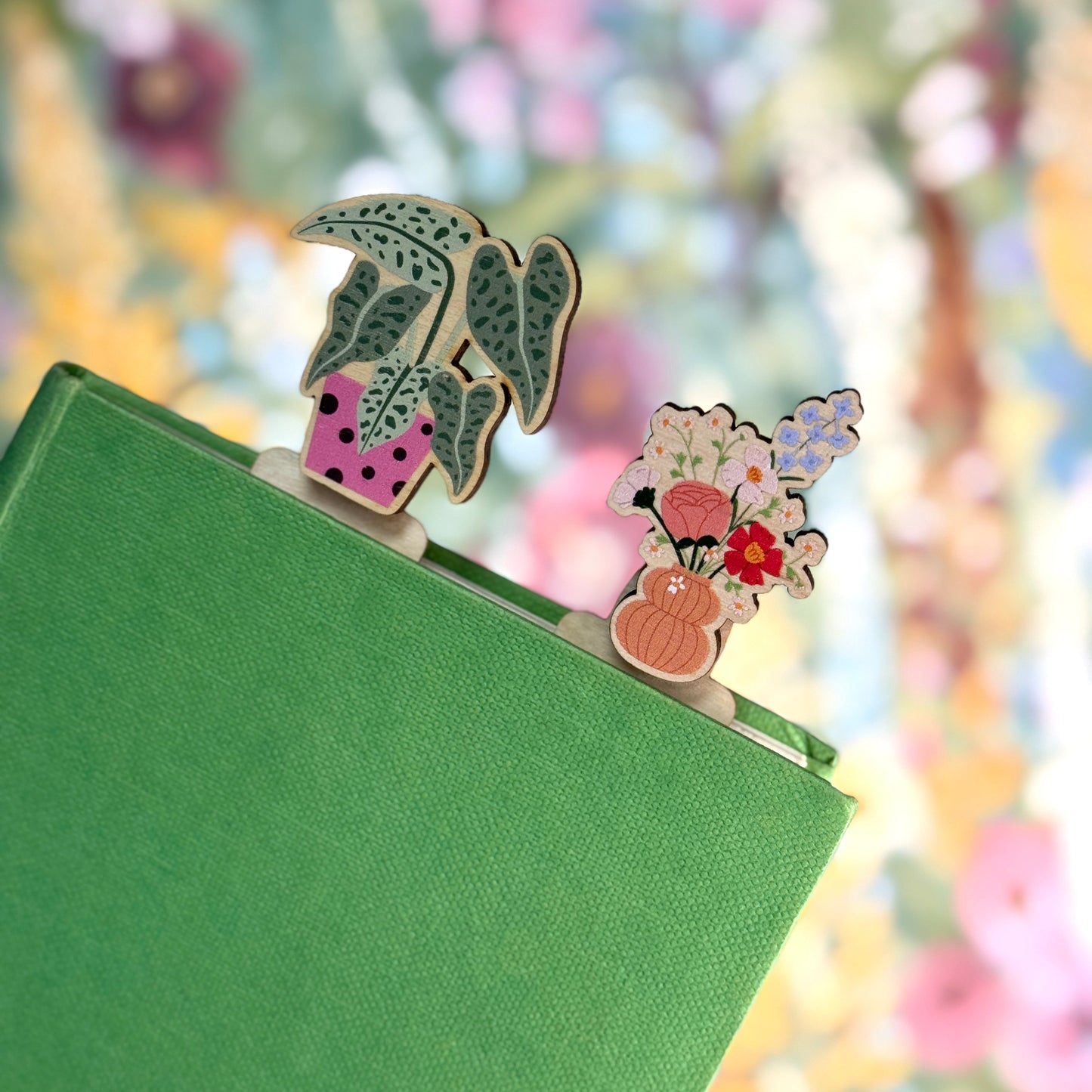 Decorative bookends with floral designs on a green book against a blurred floral background